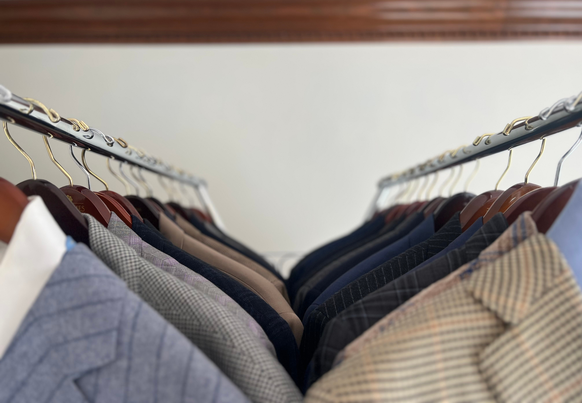 Navy business suits hanging on a wooden garment rack in the IPO showroom